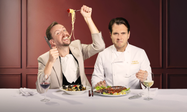 Man eet spaghetti naast man in koksschort die serieus kijkt