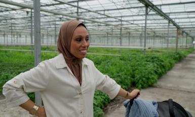 Vrouw met kinderwagen in groene kas