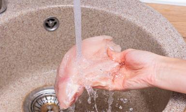 Kipfilet die gewassen wordt onder de kraan 