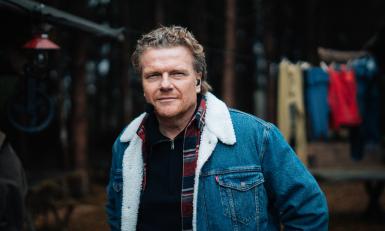 Man met spijkerjack en microfoon