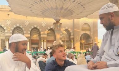 Jongen in blauwe doeken en mannen in witte doeken in moskee