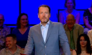 een man voor een blauwe achtergrond met publiek