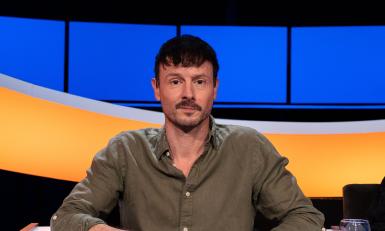 Man met donker haar en snor en groen overhemd
