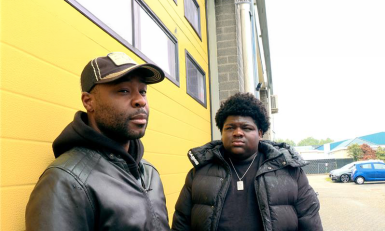 Twee mannen staan voor een gele garageklep