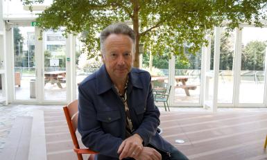 Man met grijs haar op een stoel onder een boom