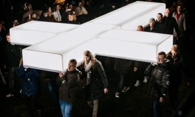 Mensen dragen het grote witte kruis van The Passion op het plein in Harlingen