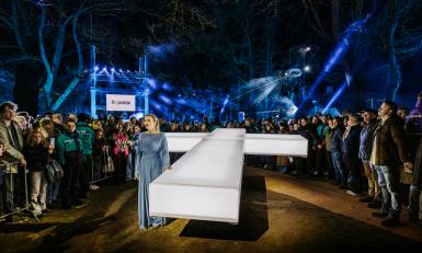 Vrouw in blauwe jurk naast wit kruis