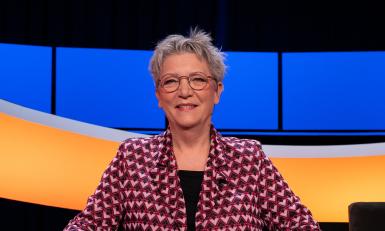 Vrouw met kort grijs haar en roze vest in studio