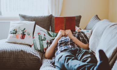 Iemand ligt lekker te chillen op de bank met een boek