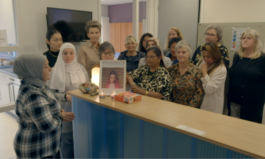 Groep vrouwen brandt een kaarsje bij een foto