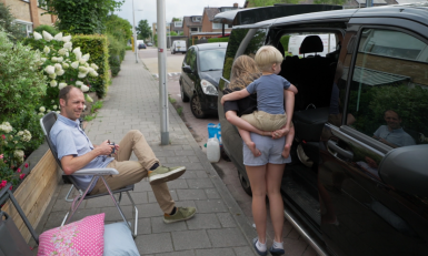 Man zit naast open bus met meisje met kind op rug