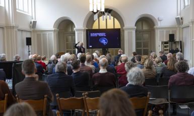 Publiek luisteren naar spreker in zaal