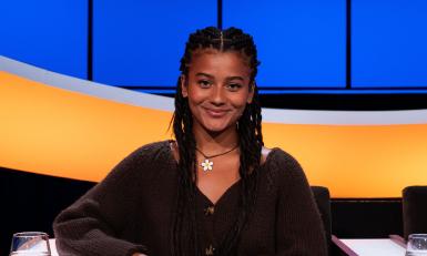 Jonge lachende vrouw met zwart haar en bloemenketting