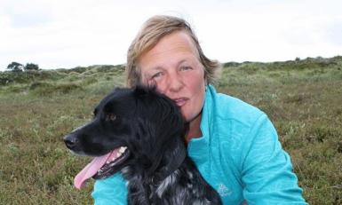 Een vrouw met haar hond tussen de duinen