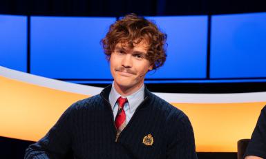 Man met krullen en blauw vest met stropdas