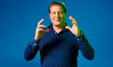 Leon Mazairac poseert voor een blauwe achtergrond in een blauwe trui