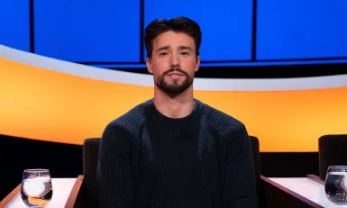 Jonge man met zwart haar en zwarte baard in donkerblauwe trui