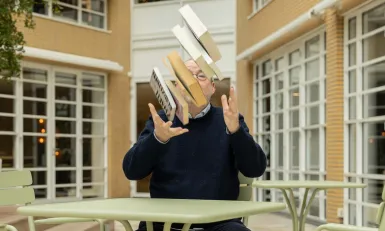 Man gooit een stapel met boeken de lucht in