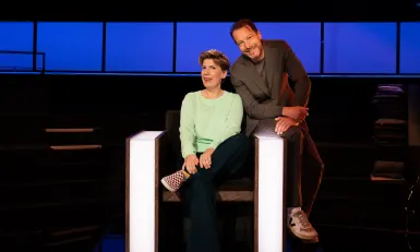 Vrouw zit in stoel met man op de leuning in een studio