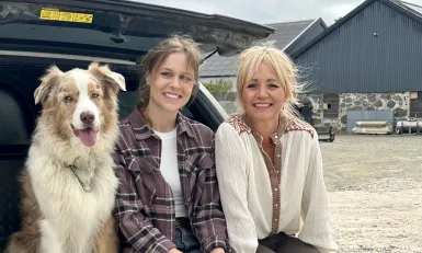 een hond en twee vrouwen zitten in de achterbak van een auto