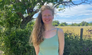 Vrouw met topje lachend voor heg