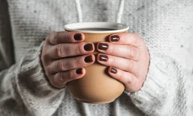 Twee handen houden een kop thee vast