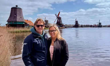 Man en vrouw staan naast elkaar voor Hollandse molens